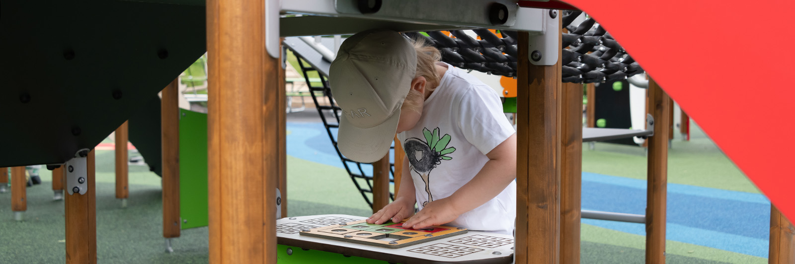 A young child is playing tic tac toe on a playground play panel.